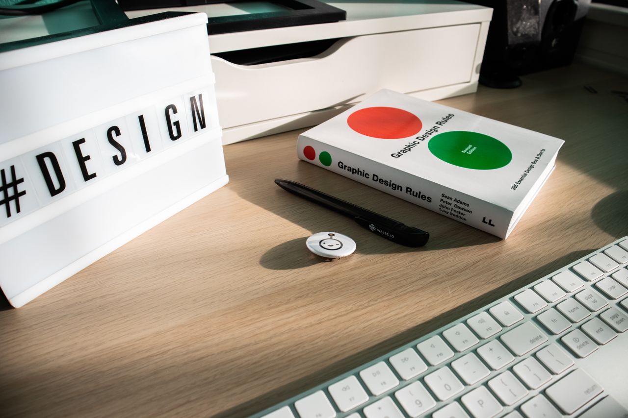 team-03 A modern desk setup featuring design elements like a book, #DESIGN sign, and accessories.