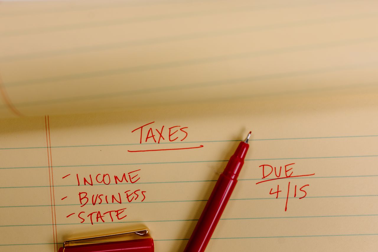 services-02 Close-up of tax-related notes on a yellow legal pad with red pen, highlighting important due dates.